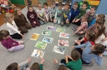 Dzieci szescioletnie z grupy IX w kregu z ilustracjami o niepelnosprawnosciach.