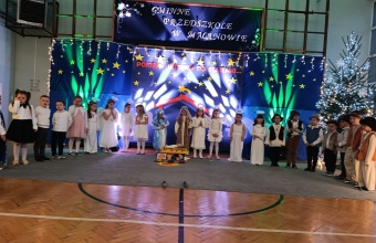 Dzieci w swiatecznej aranzacji spiewaja kolede.