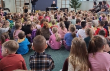 Dzieci sluchaja spiewajacego artysty.