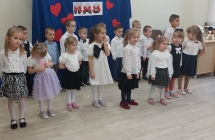 3. Dzieci stoja na tle napisu KOCHAMY WAS.