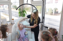 7. Dziewczynka na fotelu ma zalozony czepek ochronny na glowie.