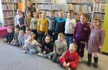 Zdjecie grupowe na tle regalow z ksiazkami.