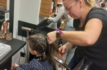 Pani fryzjerka zaplata dziewczynce warkocze.