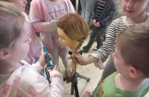 Dziewczynki cwicza zaplatanie warkoczy na modelu.