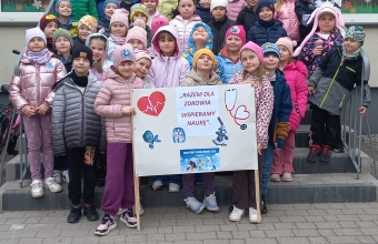 Szesciolatki z gr.VIII i IX przed budynkiem przedszkola z transparentem.