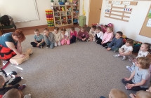 Pani ratownik pokazuje jak wykonuje sie resustytacje.