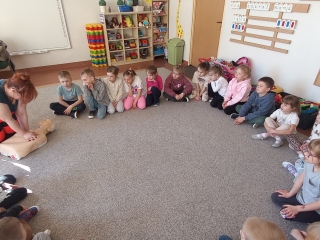 Pani ratownik pokazuje jak wykonuje sie resustytacje.