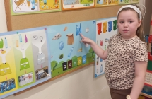 Dziewczynka wskazuje na tablicy demonstracyjnej jak segregowac odpady.