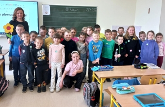 Zdjecie szesciolatkow z p. nauczycielka na tle tablicy szkolnej.