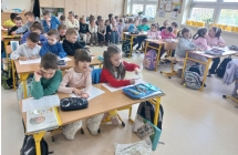 Szesciolatki w lawkach szkolnych wykonuja karty pracy.