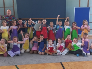 Zdjecie grupowe w kolorowych fartuszkach z instruktorem.