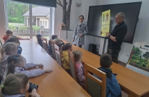 Pan lesnik prezentuje dzieciom tabliczke zakazujaca wstepu do lasu i omawia zasady bezpiecznego poruszania sie po lesie.