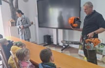Pan lesnik pokazuje dzieciom sprzet wykorzystywany w pracach lesnych.