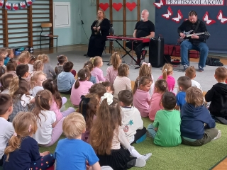 Dzieci sluchaja gry na gitarze elektrycznej.