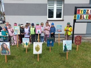 Szesciolatki przed budynkiem - obok napisu Tydzien Bibliotek.