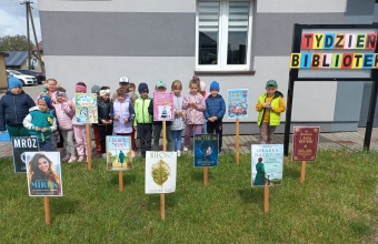 Szesciolatki przed budynkiem - obok napisu Tydzien Bibliotek.