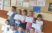 Prrzedszkolaki z gr. IX z dyplomami na tle prac plastycznych Nie pal przy mnie