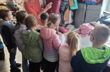 Dzieci ogladaja manekina, ktory sluzy do prezentowania uszytych ubran.