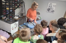 Pani krawcowa pokazuje dzieciom stoisko do prasowania. dzieci ogladaja szpule z kolorowymi nicmi.
