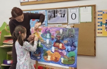 Dziewzynka z pomoc¦u Pani przykleja sylwet¦Ö Czuciaka na plakacie projektowym.