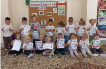 Maluszki z dyplomami za udział w zabawach na tle napisu Dzien Kropki.