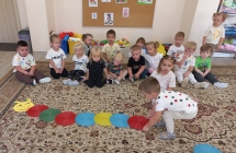 Dzieci z gr I. ukladają na dywanie gasienicę z kolorowych kół.