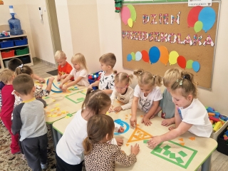Dzieci z gr I podczas zabawy figurami przy stolikach..