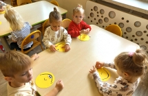 Dzieci z gr. I przy stolikach podczas wykonywania emotek.
