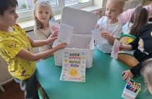Dzieci wrzucaja laurki dla kolegow i kolezanek z grupy do pudelka zyczliwosci